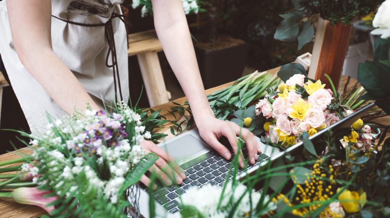 Crop florist surfing laptop in workshop