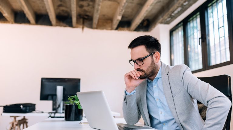 Serious businessman looking at laptop screen.